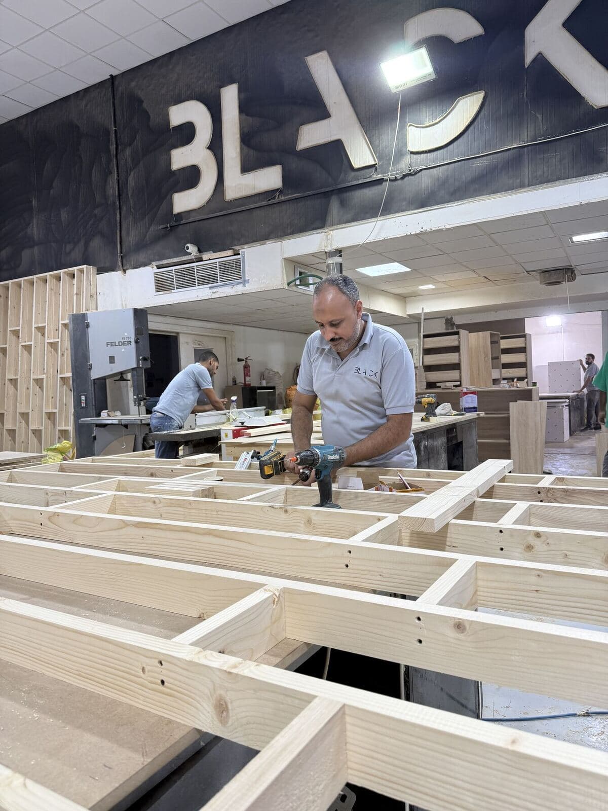 A team member building a wooden frame in the factory